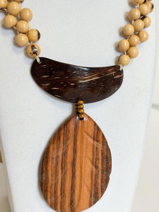 Close-up of açaí seeds, cuia elements and muiracatiara wood pendant in handmade necklace.