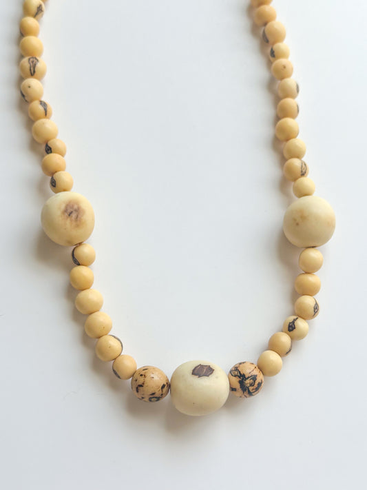 Close-up of natural açaí seeds and paxiúba wood beads in handcrafted Amazon necklace.