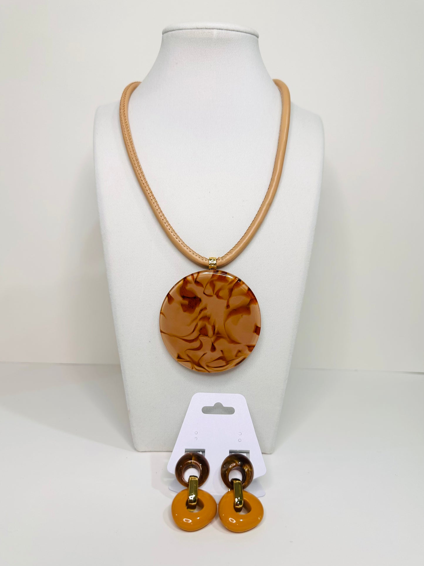 Jewelry set with a beige necklace and earrings on a mannequin bust.