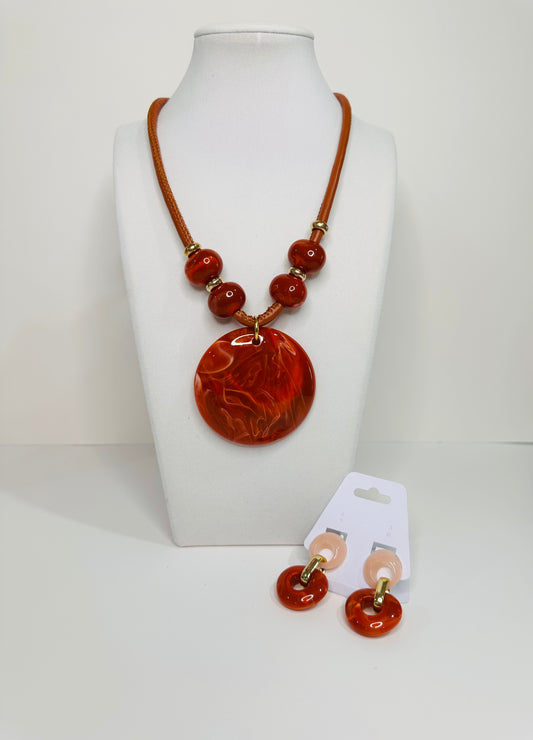 Necklace and earrings set with large round amber pendant on a white mannequin bust.