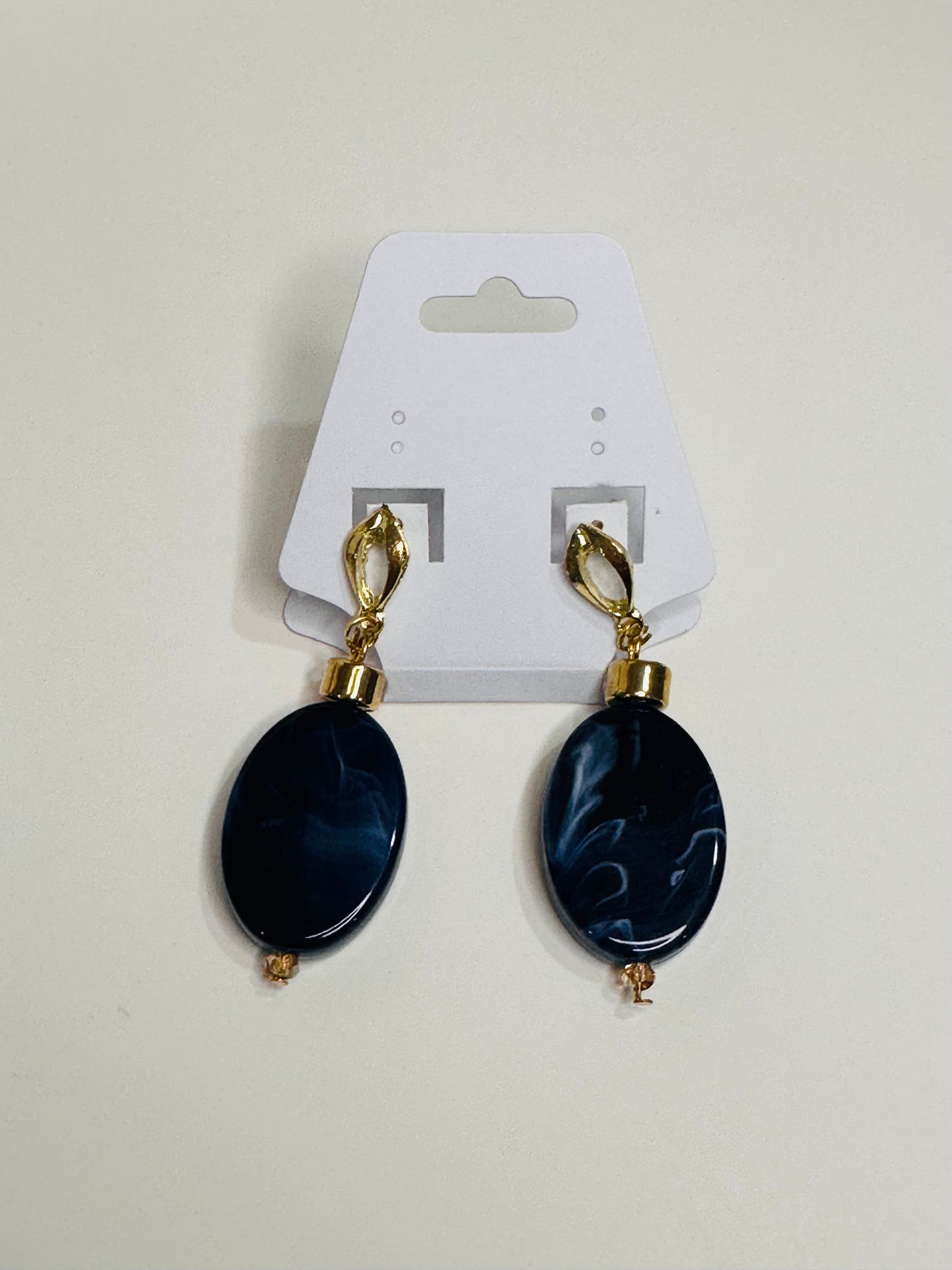 Pair of blue oval earrings with gold accents on a white card.