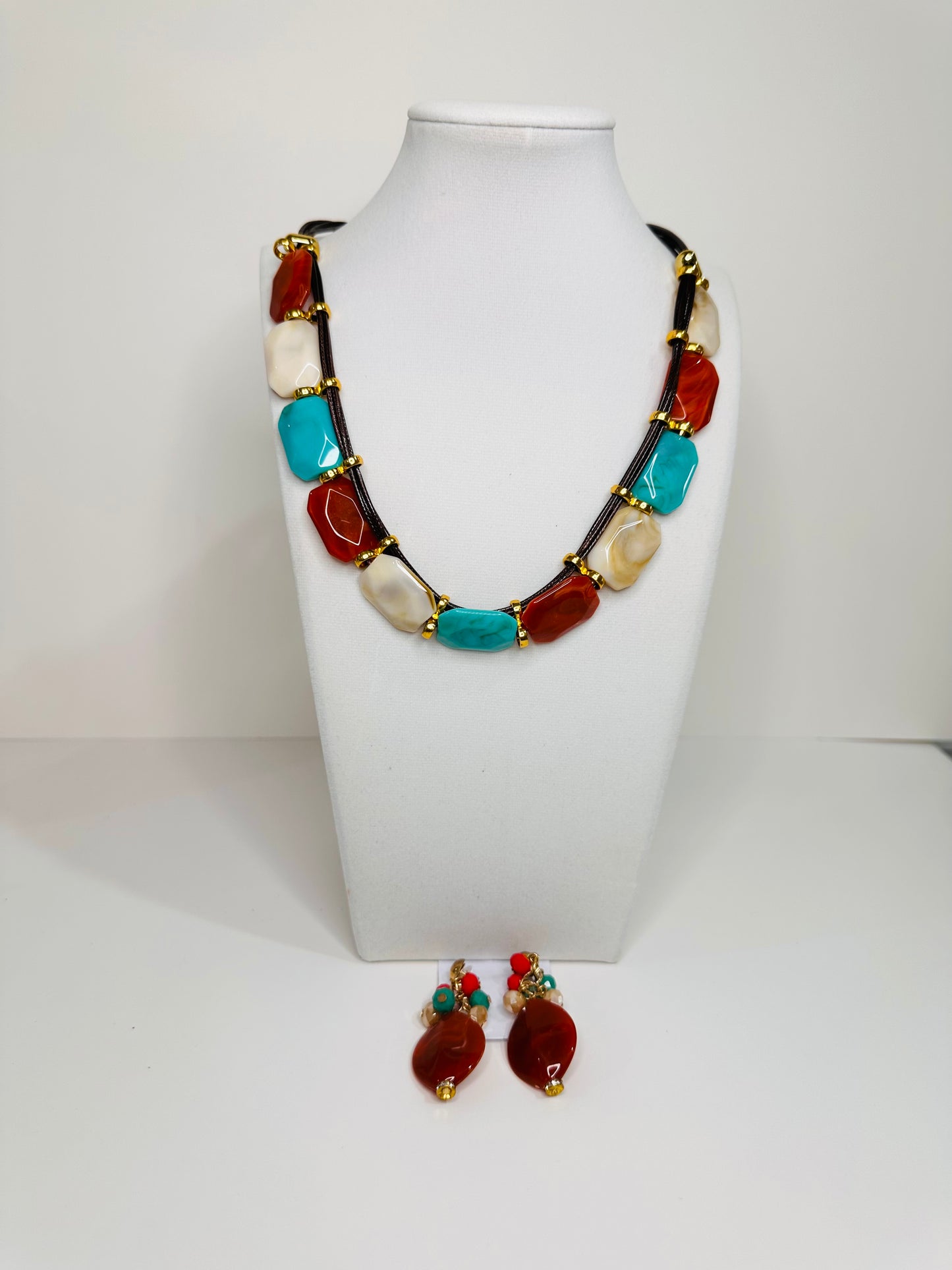 Necklace and earrings with multicolored resin on a white stand