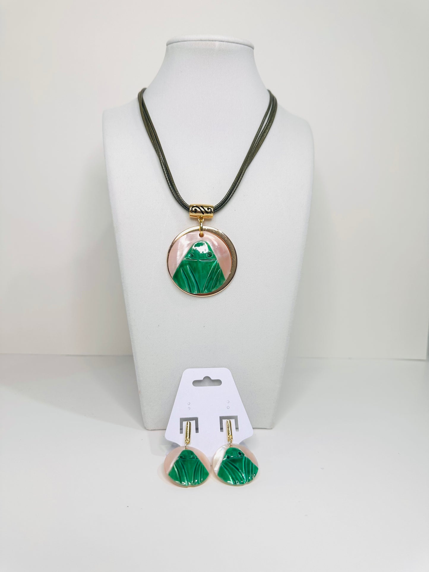 Necklace with green and mother of pearl pendant and matching earrings on a white background