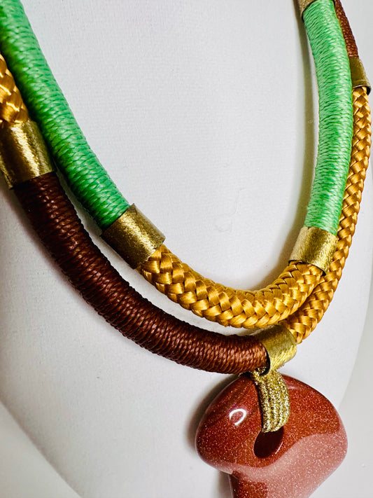 Sol Terra statement necklace featuring sunstone-inspired pendant with layered mustard and green bead strands