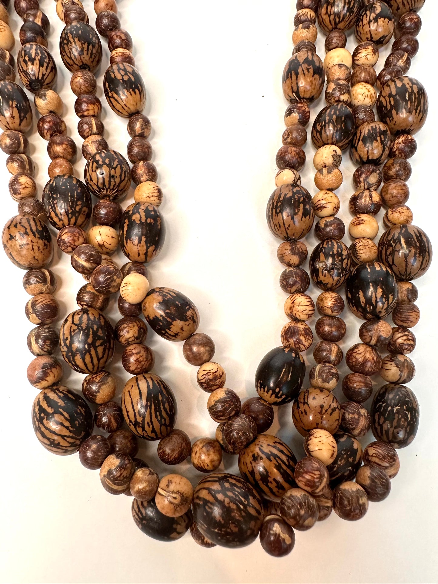 Three strands of brown and black beaded necklaces made of acai and paxiuba