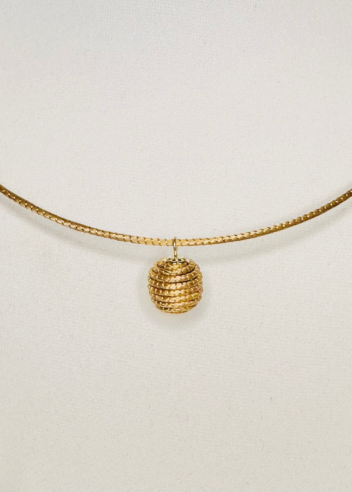 Minimalist golden grass pendant woven from capim dourado