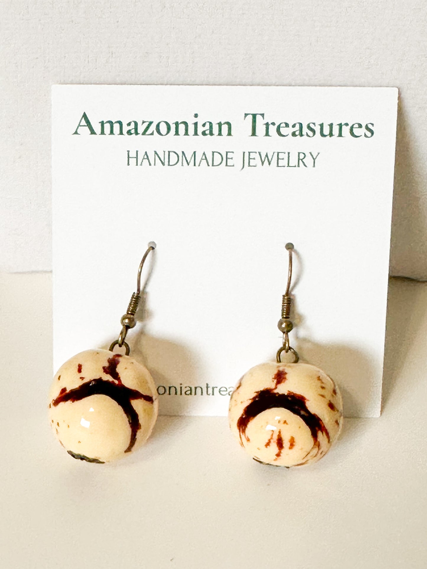 Close-up Beige jarina seed earrings with paxiúba beads.