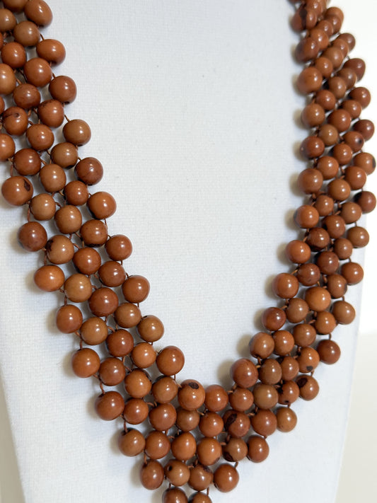 Close-up of polished dyed açaí seeds used in handmade Brazilian necklace. Brown
