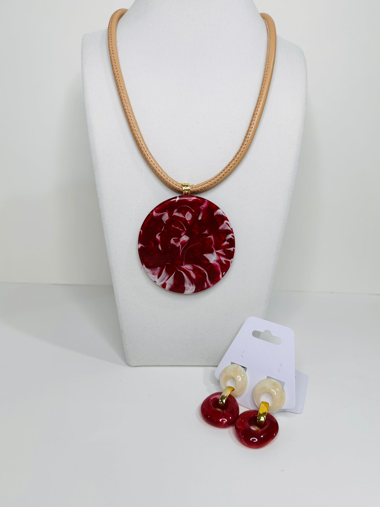 Jewelry set with matching earrings in white and red pendant on a white background