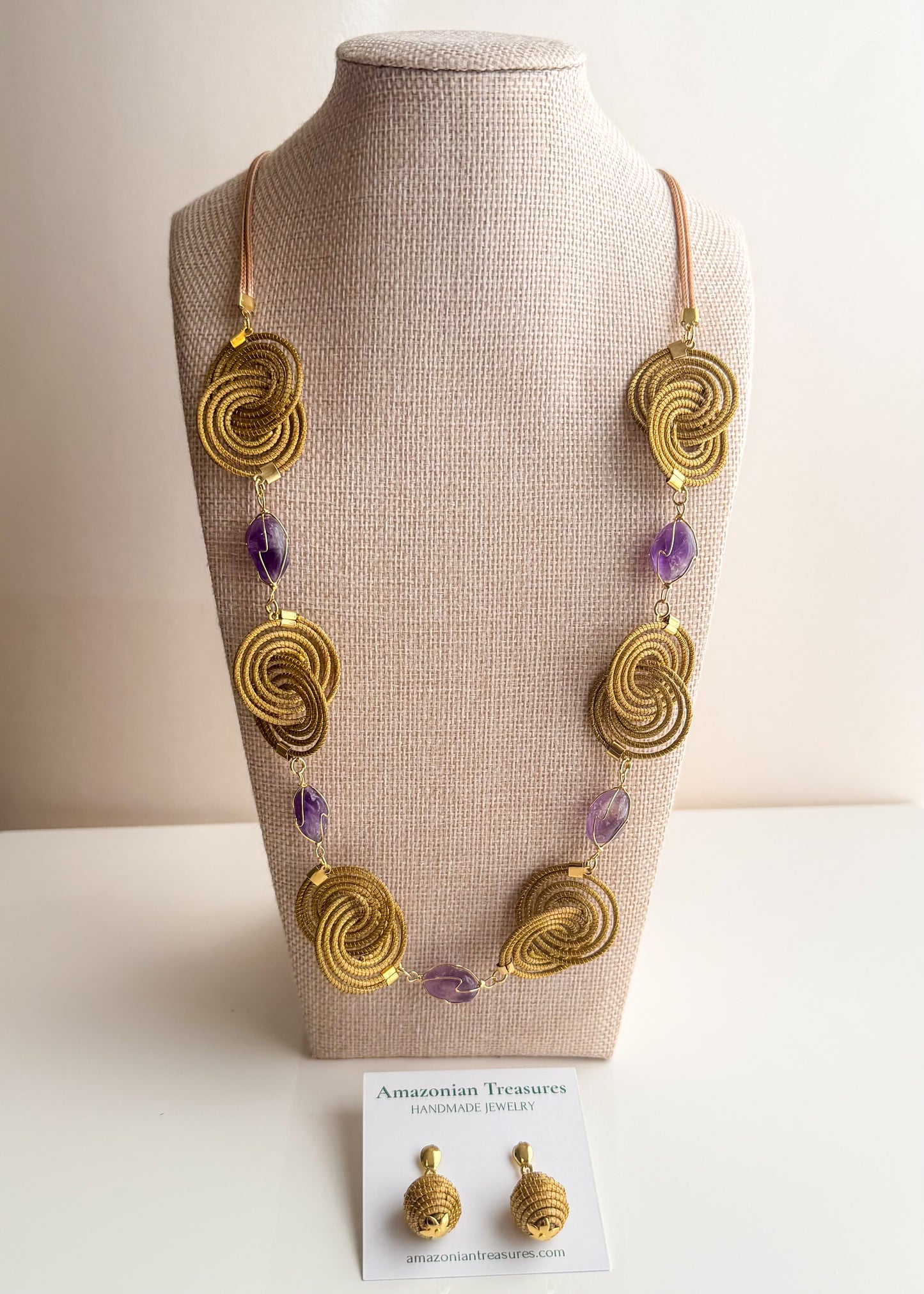 Espiral Dourada Set featuring golden grass spiral necklace and matching earrings handcrafted by quilombola artisans in Brazil. Amethyst