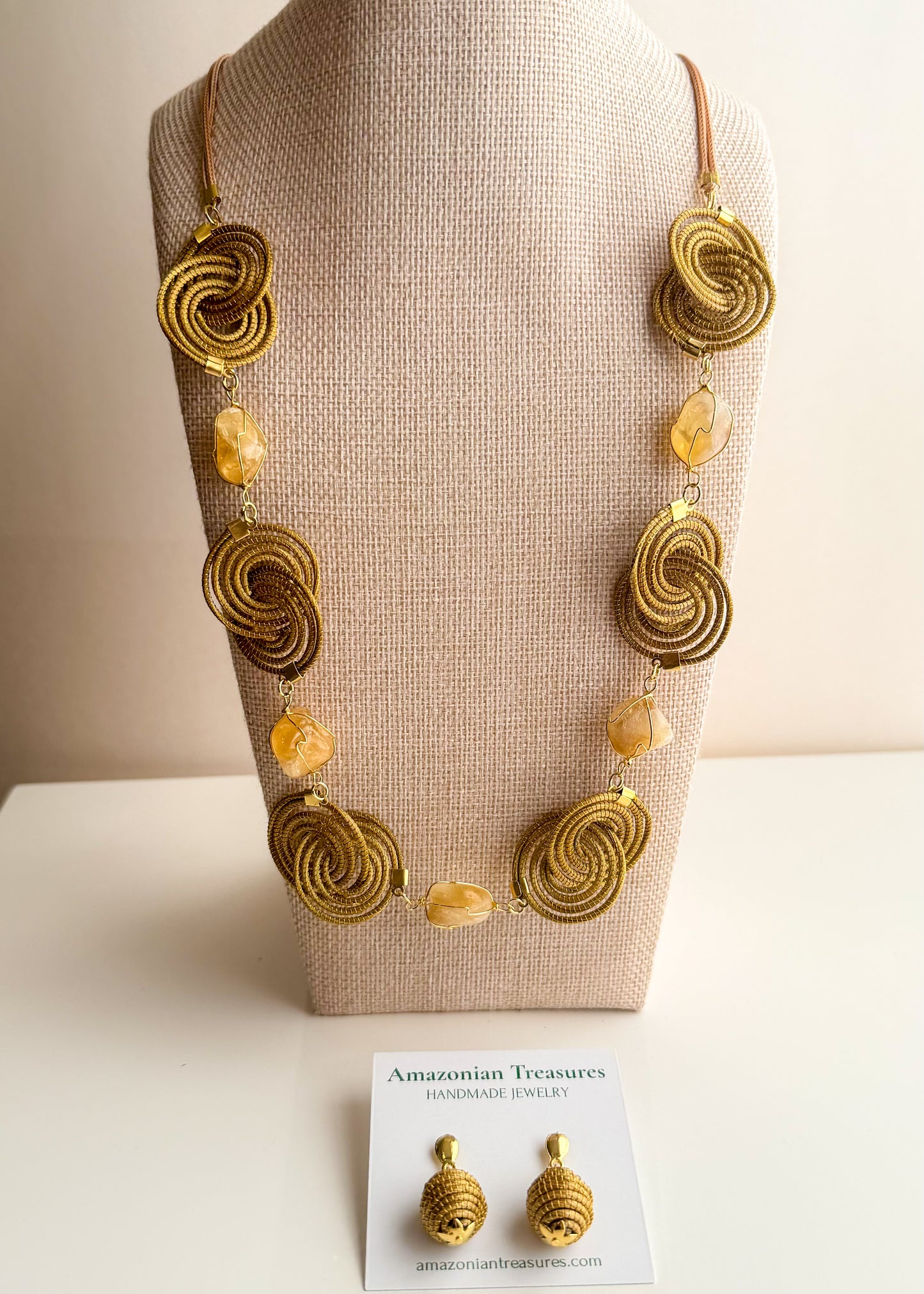 Espiral Dourada Set featuring golden grass spiral necklace and matching earrings handcrafted by quilombola artisans in Brazil. Citrine