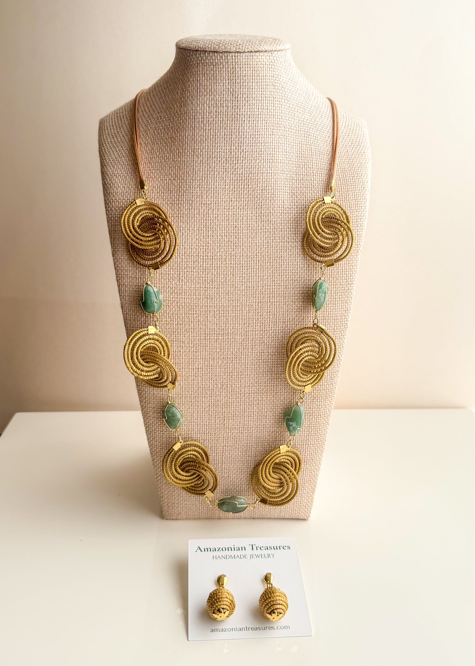 Espiral Dourada Set featuring golden grass spiral necklace and matching earrings handcrafted by quilombola artisans in Brazil. Green Aventurine