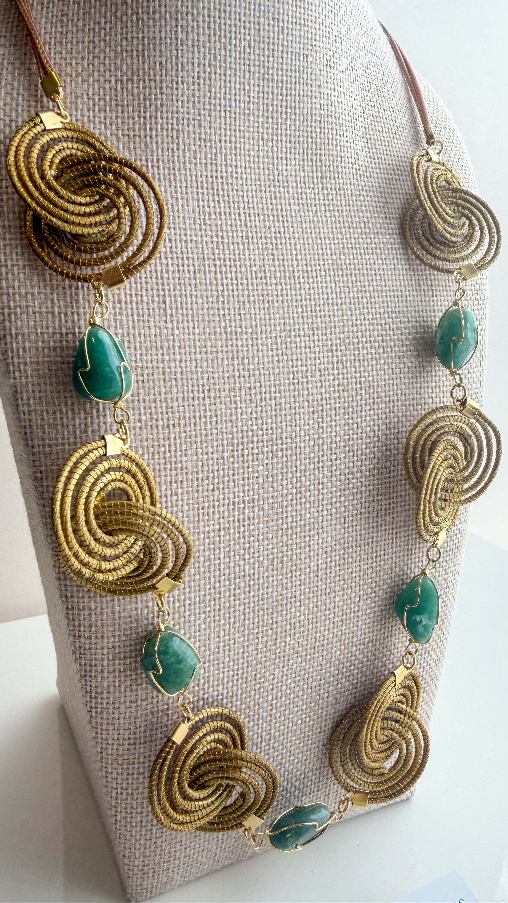 Espiral Dourada Set featuring golden grass spiral necklace and matching earrings handcrafted by quilombola artisans in Brazil. Green Aventurine