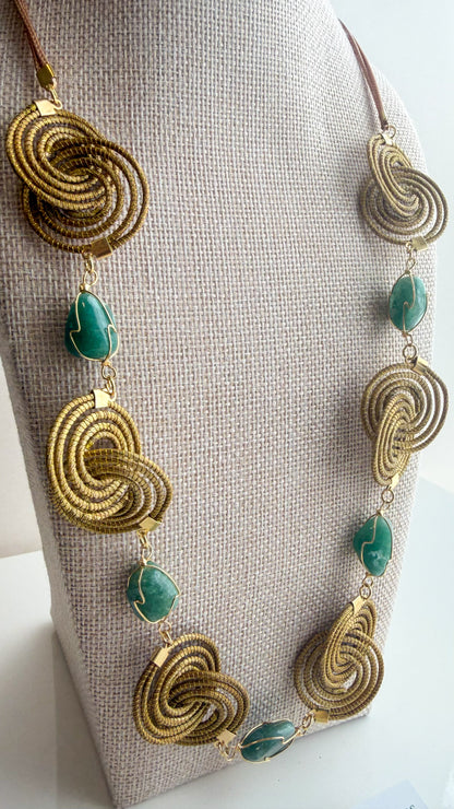 Espiral Dourada Set featuring golden grass spiral necklace and matching earrings handcrafted by quilombola artisans in Brazil. Green Aventurine