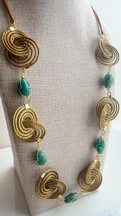 Espiral Dourada Set featuring golden grass spiral necklace and matching earrings handcrafted by quilombola artisans in Brazil. Green Aventurine