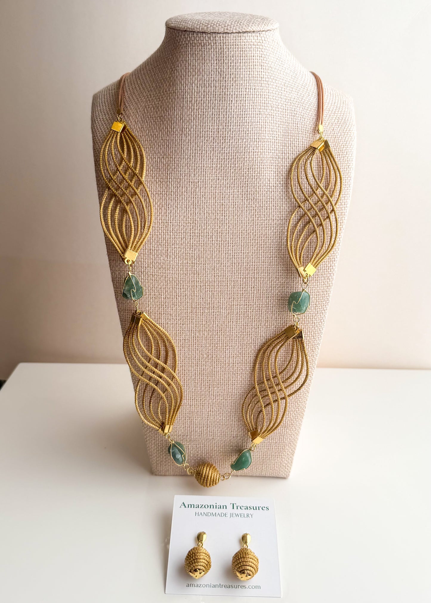 Golden grass flowing necklace with green gemstone handcrafted by quilombola artisans.