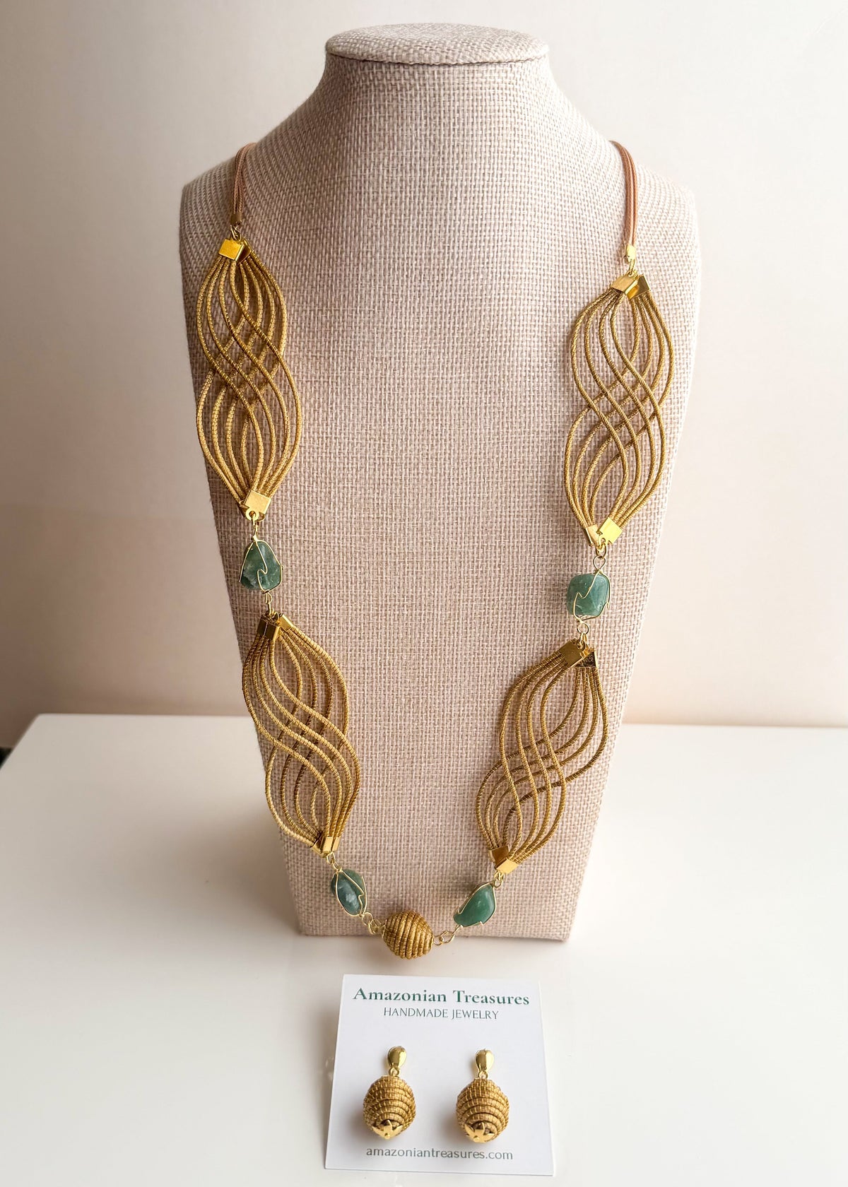 Golden grass flowing necklace with green gemstone handcrafted by quilombola artisans.