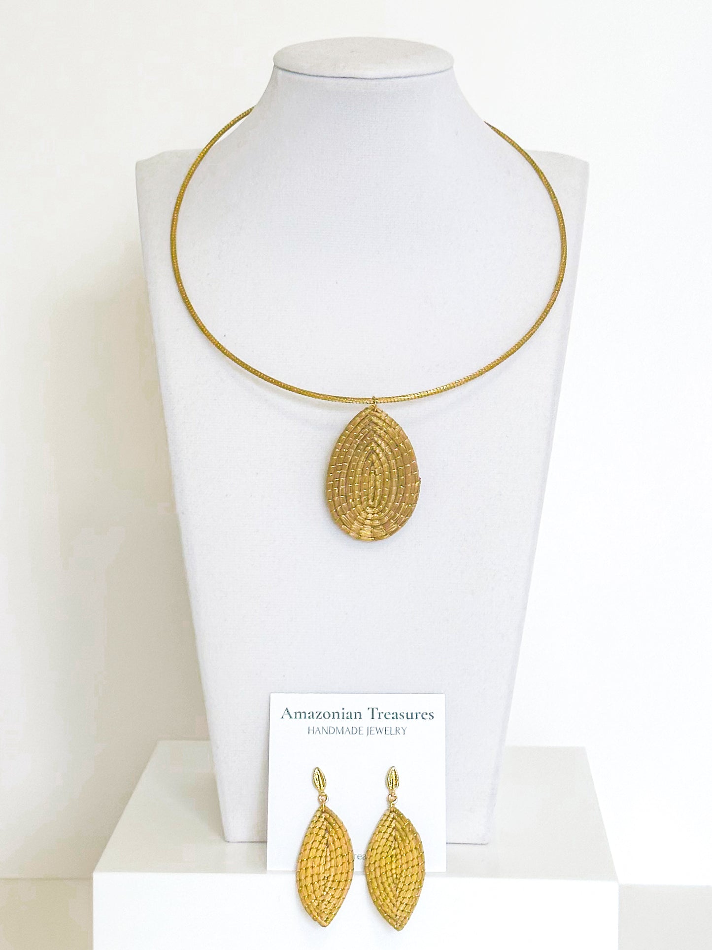 Golden grass leaf necklace and earrings set handcrafted by quilombola artisans using capim dourado.