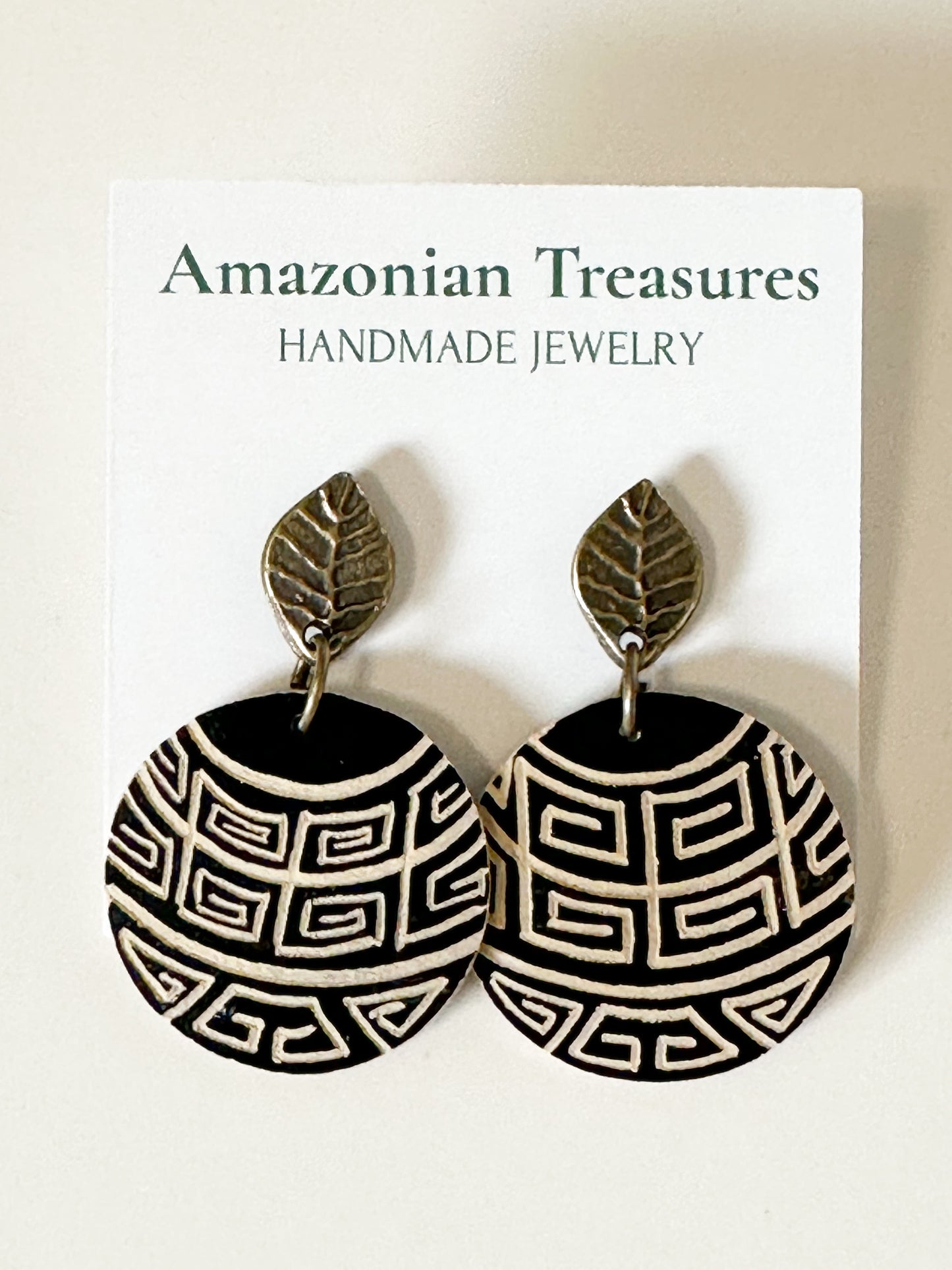 Handcrafted cuia gourd earrings with traditional Amazon-inspired motifs.