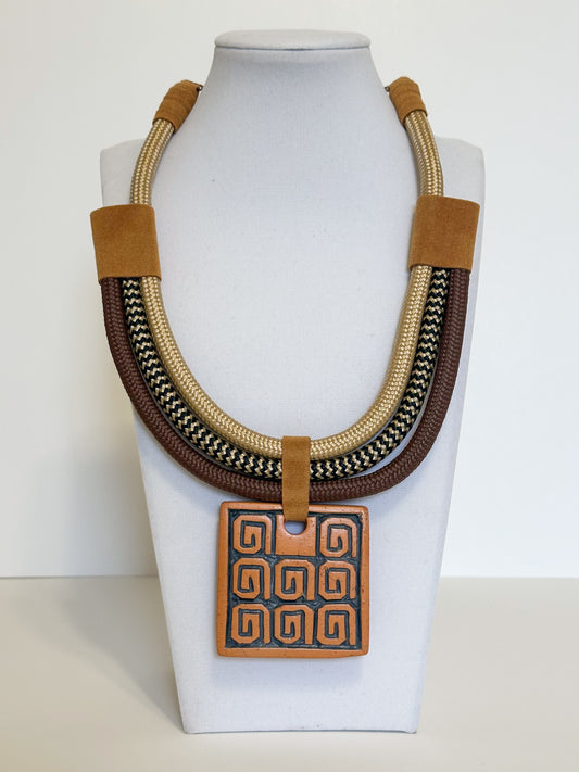 Handmade ceramic pendant necklace with Indigenous-inspired patterns, rope cords and suede accents.