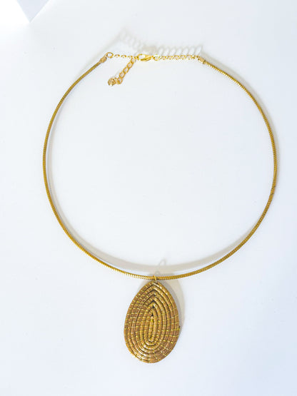 Handwoven golden grass necklace with leaf pendant made from capim dourado.