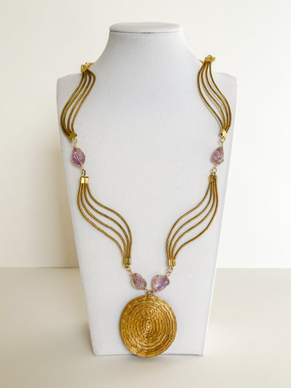 Lua Dourada golden grass medallion necklace featuring handwoven circular pendant with amethyst accents.