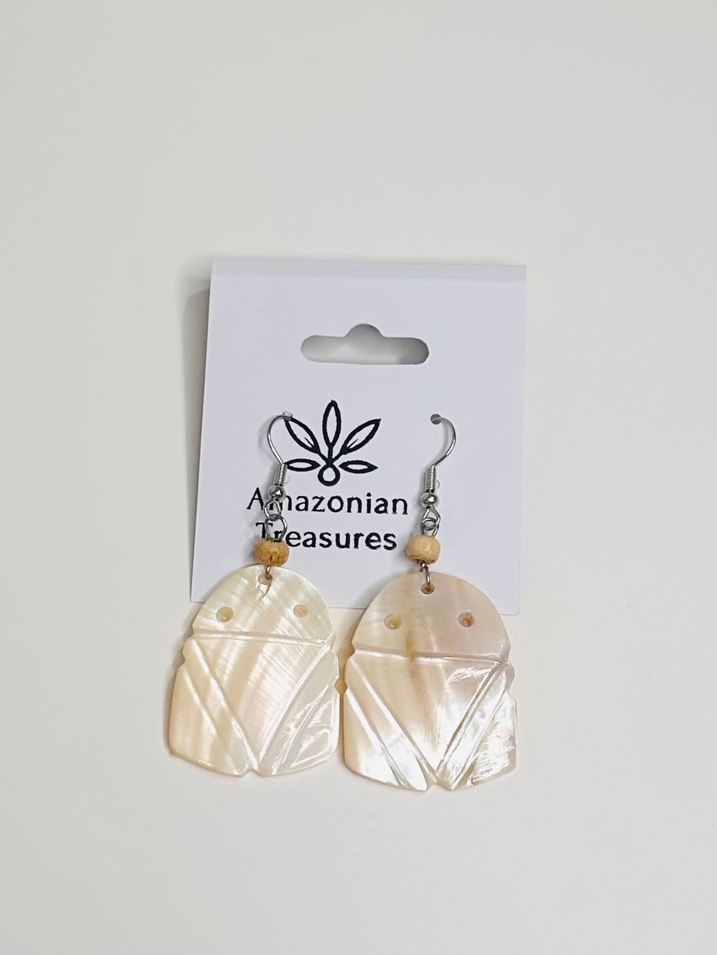 Pair of Muiraquita earrings made of mother of pearl on a 'Amazonian Treasures' branded card