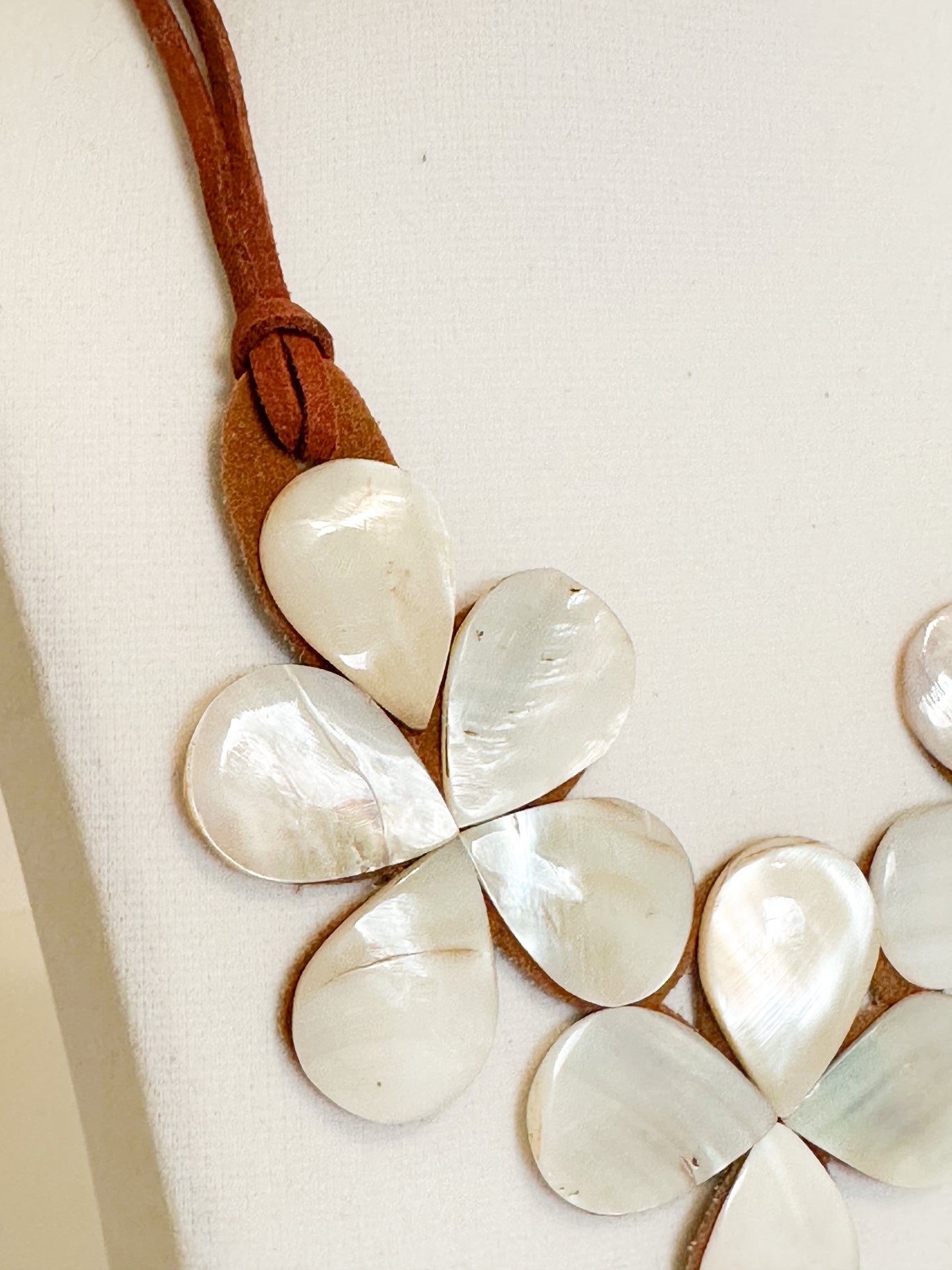 Mother of pearl shell flower necklace mounted on suede backing.