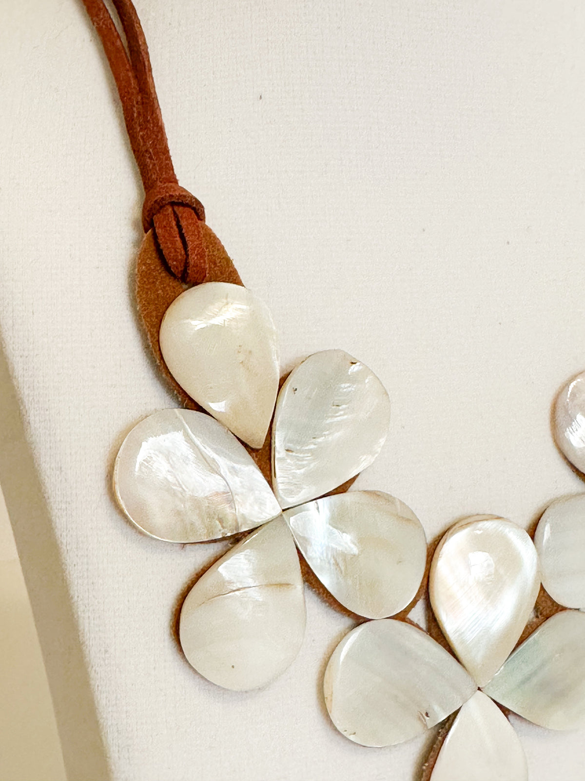 Mother of pearl shell flower necklace mounted on suede backing.