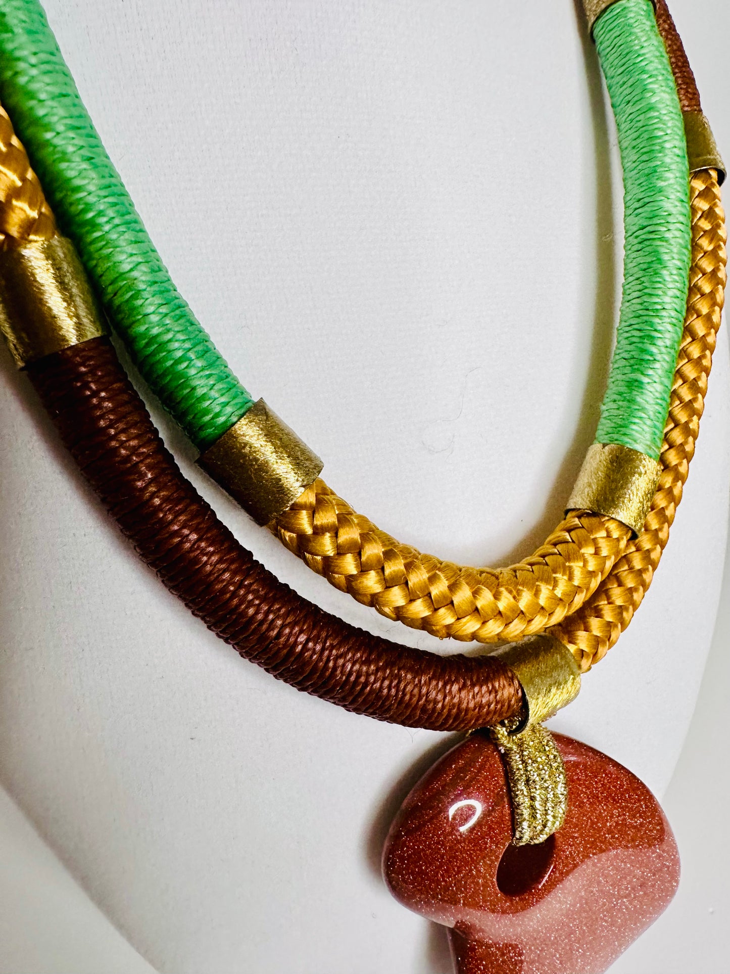Sol Terra statement necklace featuring sunstone-inspired pendant with layered mustard and green bead strands
