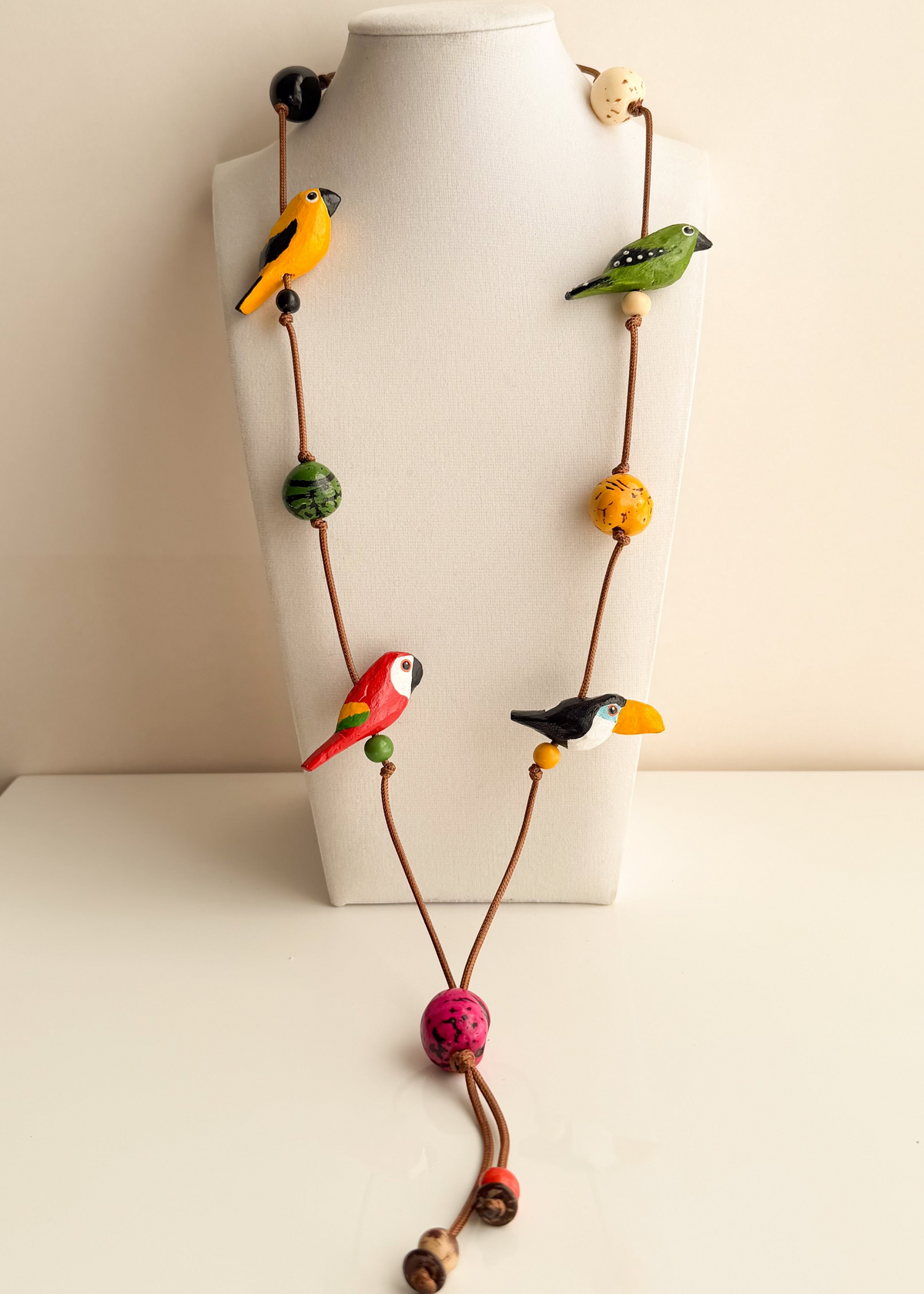 Amazonian Treasures Amazon Birds necklace featuring hand-tinted Buriti and Paxiúba wood bird charms on an earthy cord.