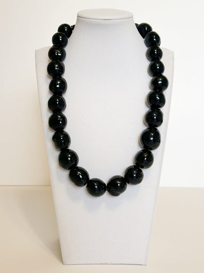 Amazonian Treasures handmade necklace featuring polished black paxiúba seeds on a white display bust.