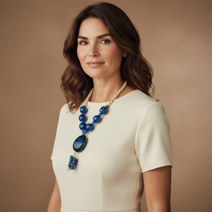 Amazonian Treasures statement necklace with blue acai seeds and jarina on a woman wearing a cream dress.