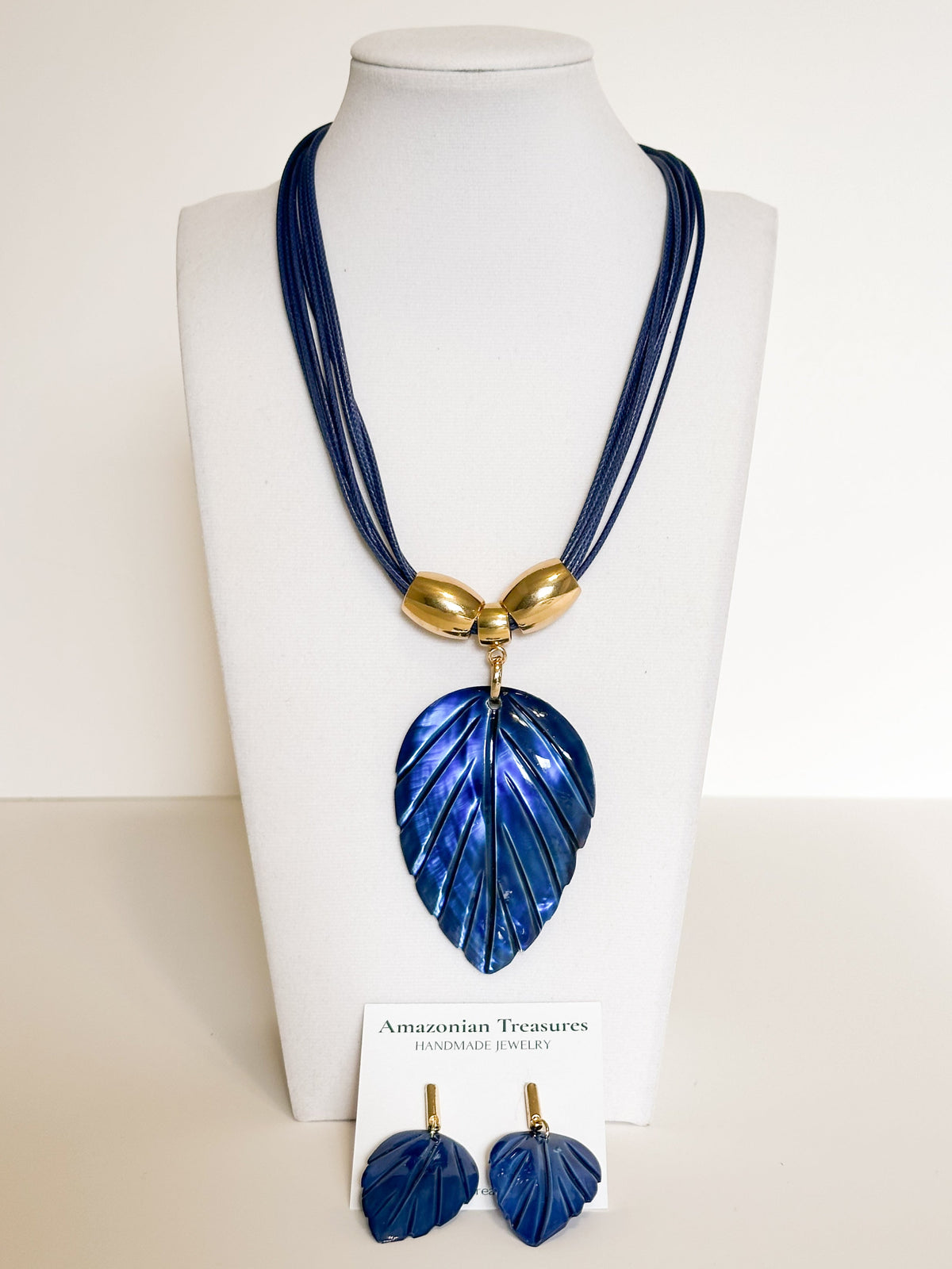 Amazonian Treasures blue mother of pearl leaf necklace and earring set with gold-tone accents on a display bust