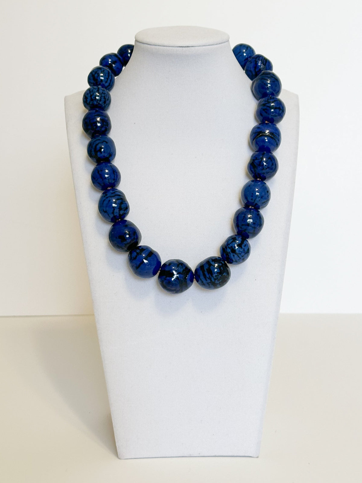 Amazonian Treasures handmade necklace featuring vibrant blue dyed paxiúba seeds with natural textures on a display bust