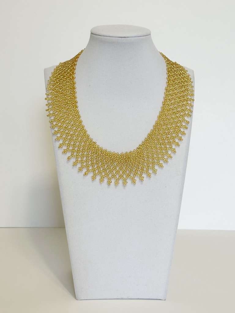 Amazonian Treasures gold glass bead collar necklace with intricate net-like weave and fringe, handmade by Borari artisans