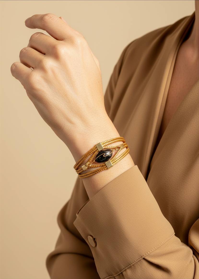 Amazonian Treasures handwoven golden grass bracelet with a dark stone accent worn on a model's wrist.