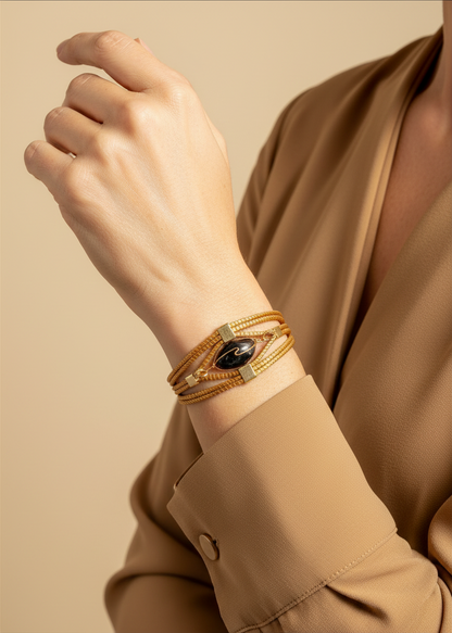 Amazonian Treasures handwoven golden grass bracelet with a dark stone accent worn on a model's wrist.