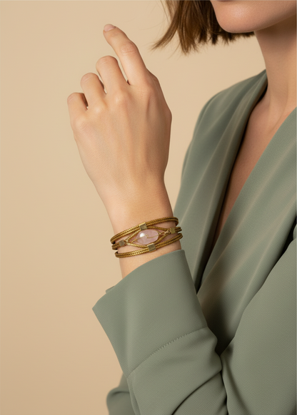 Amazonian Treasures handwoven capim dourado golden grass bracelet with a rose quartz stone accent on a woman's wrist.