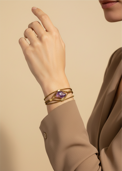 Amazonian Treasures handwoven golden grass bracelet with a purple stone accent worn on a model's wrist.