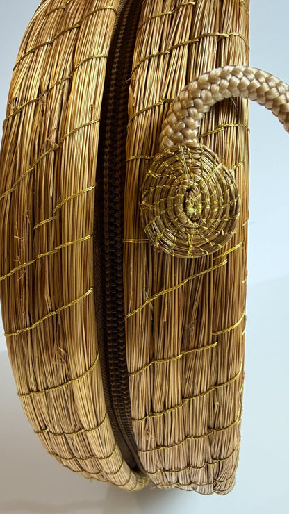 Amazonian Treasures handwoven round crossbody bag made from golden capim dourado grass with a rope strap detail
