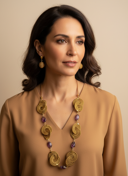 Amazonian Treasures golden grass spiral necklace and earrings set worn by a woman in a tan blouse