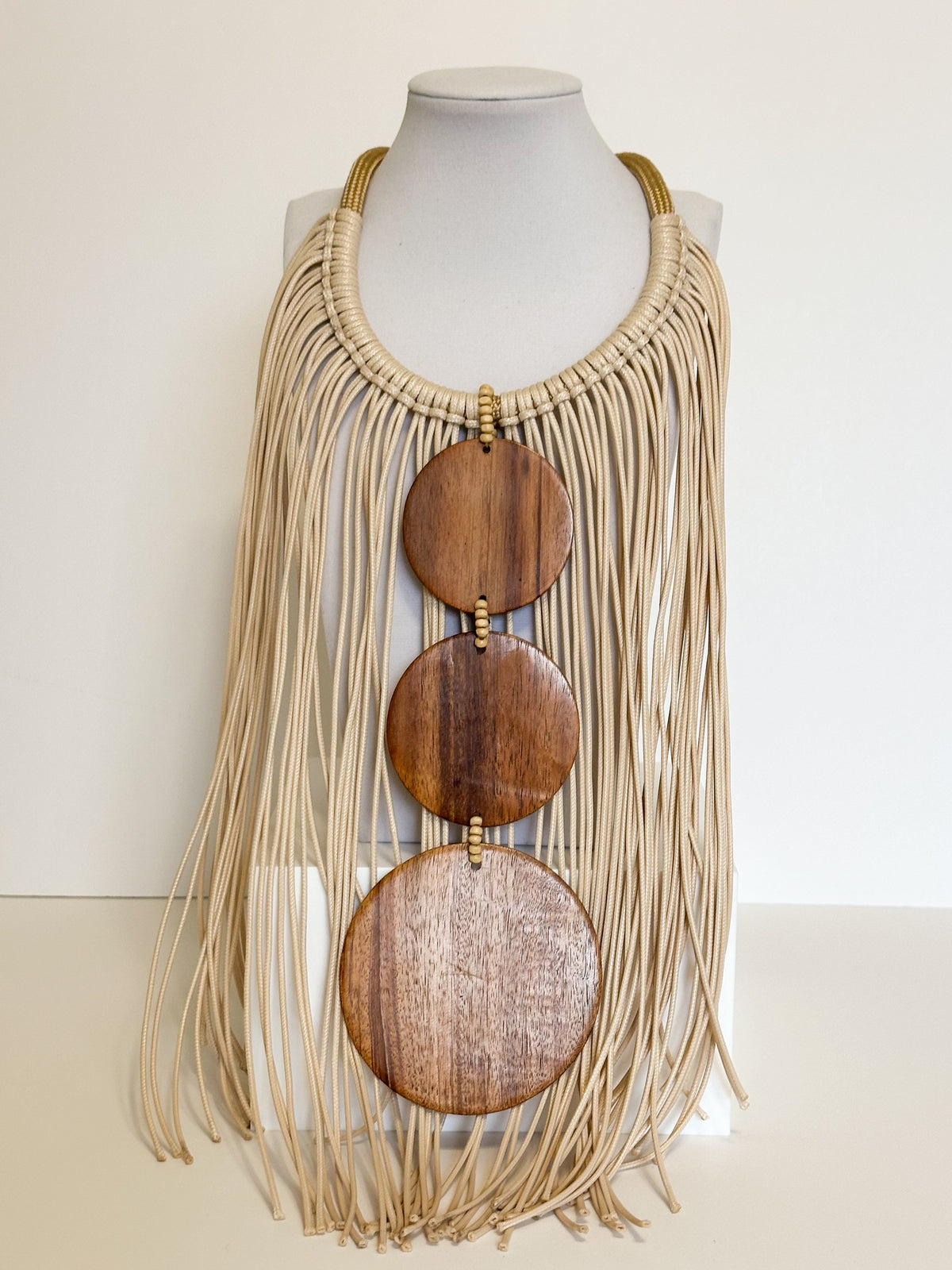 Amazonian Treasures handmade necklace featuring cascading cream cotton strands, paxiúba seeds, and three wood discs.