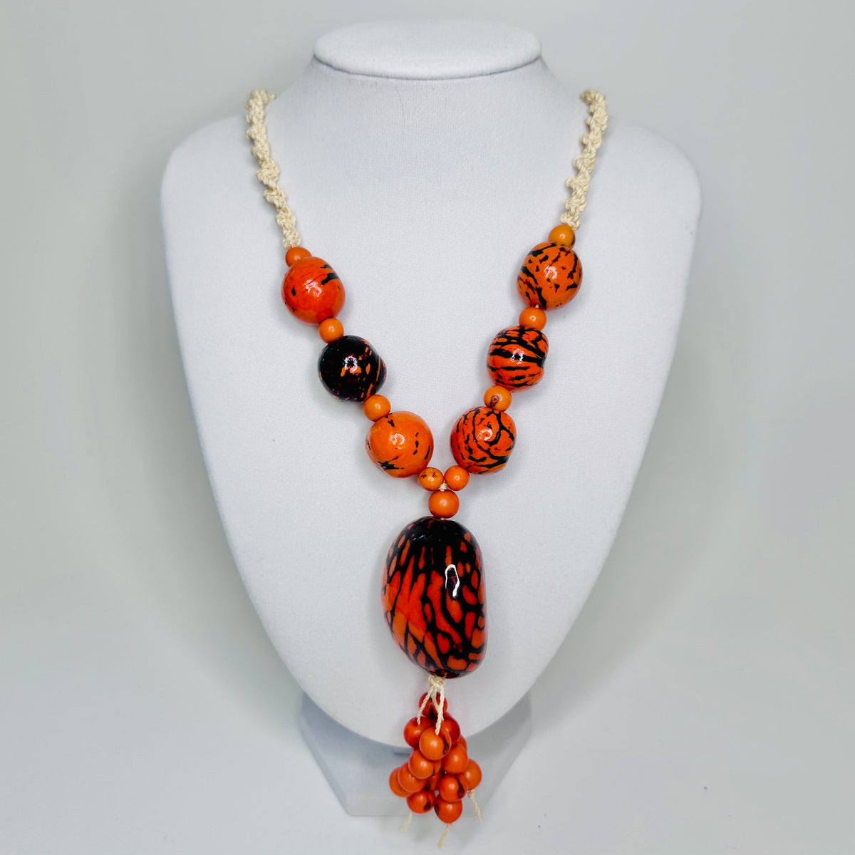 Amazonian Treasures statement necklace featuring orange and black patterned jarina seeds and tucum fiber cord.