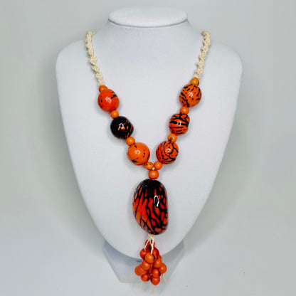 Amazonian Treasures statement necklace featuring orange and black patterned jarina seeds and tucum fiber cord.