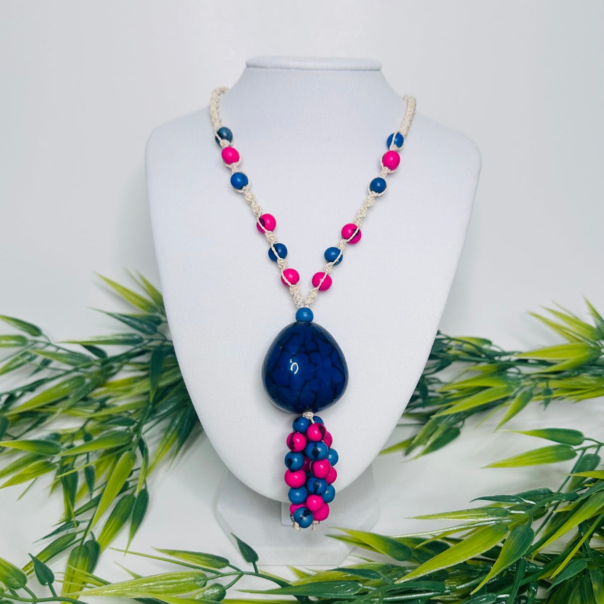 Amazonian Treasures necklace featuring blue and pink açaí seeds and a large jarina pendant on woven tucum fiber cord.