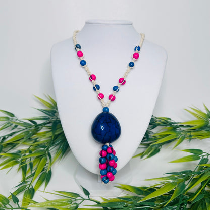 Amazonian Treasures necklace featuring blue and pink açaí seeds and a large jarina pendant on woven tucum fiber cord.