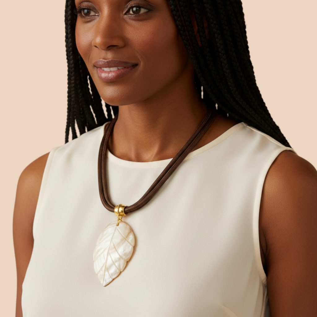 Amazonian Treasures mother of pearl leaf pendant necklace on a brown rope cord worn by a woman with braided hair.