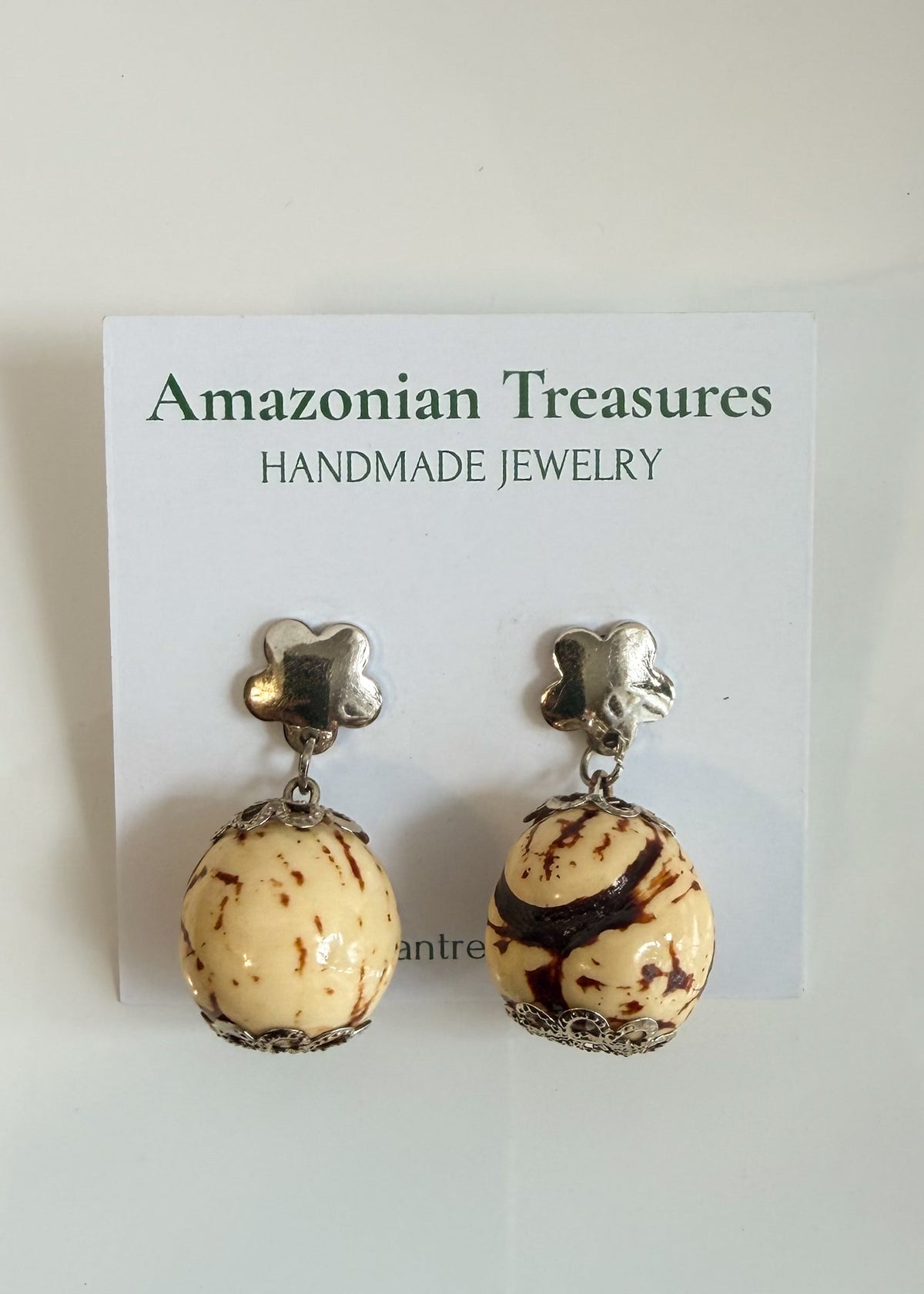 Amazonian Treasures handcrafted Paxiúba seed drop earrings with silver flower studs on a white display card