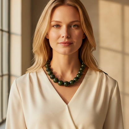 Amazonian Treasures paxiúba seed necklace in dark green worn by a woman in a cream blouse, showcasing natural textures.